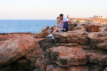 Naklejka na ściany i meble Love couple on rocks with sea view and sunset 