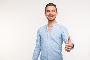 Gesture and people concept - Handsome man with smile showing thumb up on white background with copy space