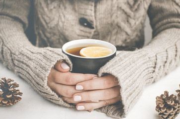 Woman in a sweater holding cup of tea