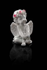 fiporcelain figurine of a seated angel, with wings, black background, reflection, Valentine's Day