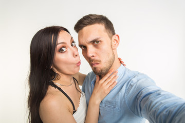 Relationship and family concept - happy funny couple taking selfie on white background