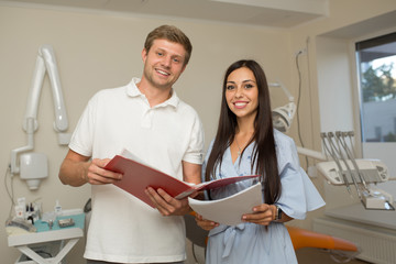 doctor and his assistant looking in folder with paper. Dental office background