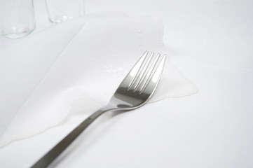 silver fork on luxury white tablecloth food dinner with glass background