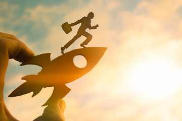Concept start up. Silhouette of a businessman with a briefcase on a rocket holds the hand of a man....