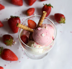 A cup of ice cream with strawberries and rolled wafers. ice cream closeup.