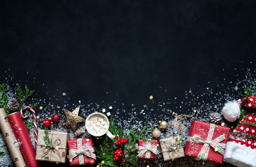 Christmas composition on a black background Christmas decorations, boxes, branches of tree, cap, Santa, star.