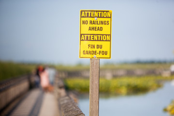 Yellow and Brown Boardwalk Sign Warning No Railing Ahead