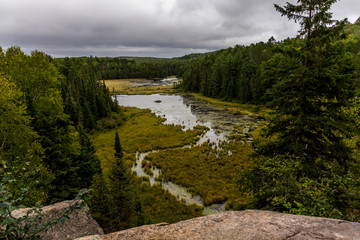 Beautiful view from a natural view point on a hill over a small river and lake in Algonquin Ontario in Canada during a cloudy day in autumn.