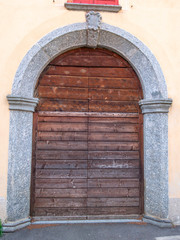 Old wooden door with a stone arch. Antique gothic design of the door trim in gray whole stone