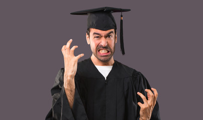 Man on his graduation day University annoyed angry in furious gesture. Negative expression on violet background