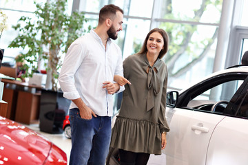 Adult couple choosing new car in showroom