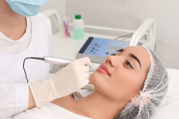 Fototapeta premium Młoda kobieta w trakcie zabiegu makijażu permanentnego ust w salonie tatuażu