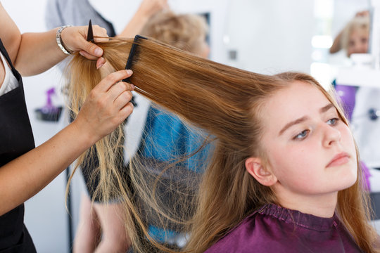 Hands of hairdresser making hairstyle for girl