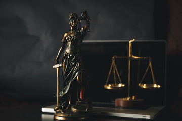 Lawyer office. Statue of Justice with scales and lawyer working on a laptop. Legal law, advice and...