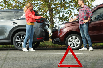 Emergency stop sign near people discussing car accident on road. Auto insurance