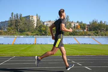 Fototapeta premium Sporty man running at stadium on sunny morning