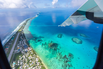 Tuvalu lagoon under wing of an airplane. Aerial view of Funafuti atoll and the airstrip of International airport in Vaiaku. Fongafale motu. Island nation in Polynesia, South Pacific Ocean, Oceania. - obrazy, fototapety, plakaty