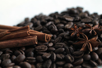 Coffee beans and cinnamon sticks on white background.