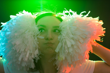 Dancing, cheerleading and people concept - funny young girl in darkness under colourful light with...