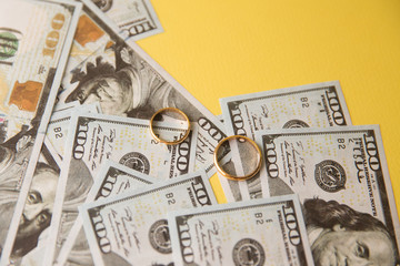 Golden wedding rings on dollars bill background. Divorce or infidelity concept