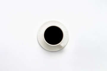 White cup with saucer and black coffee on a white background. Flat lay, top view
