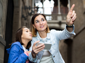 Mother and daughter consulting guide in phone