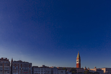 Saint Mark's Bell Tower over Venetian houses under blue sky at sunset, in Venice, Italy