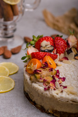 White cake with fruit, berries and almonds on a light background. Piece of cake.