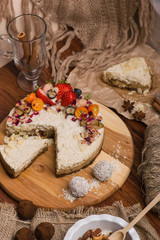 Cake with berries and fruits on a wooden table. Candy, nuts, cinnamon on a burlap.