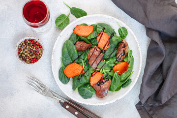 Warm spinach salad with chicken liver and baked pumpkin with spices and balsamic. Delicious dinner with red wine for gourmets.