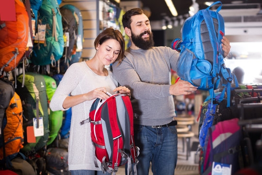 young couple examining rucksacks in sports equipment store