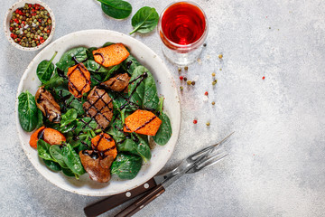 Warm spinach salad with chicken liver and baked pumpkin with spices and balsamic. Delicious dinner with red wine for gourmets.