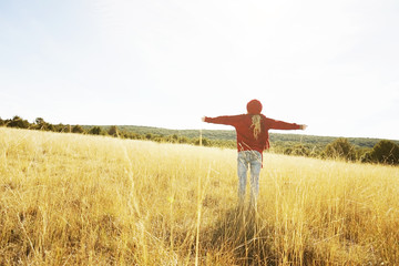 Back view of a young woman in nature in a sunny autumn day