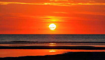 Roter Sonnenuntergang am Meer an der Nordsee mit Strand im Vordergrund
