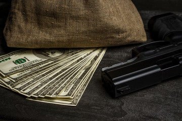 Pistol on the table near the bag with dollars