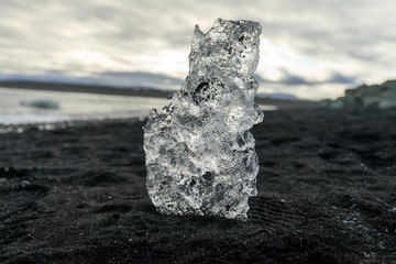 Piece of glacier ice on the black volcanic beach nearby the Glacier Lagoon in Iceland