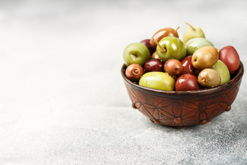 Mixed marinated olives (green and purple) in ceramic bowl. Selective focus. Copy space