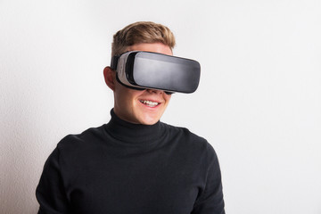 Portrait of a young man with virtual reality goggles in a studio.