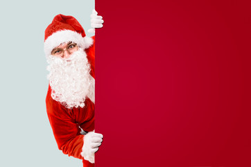 Santa Claus is looking out of colorful advertisement board and copy space