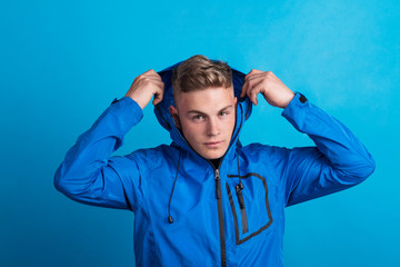 Portrait of a young man with blue anorak in a studio. Copy space.