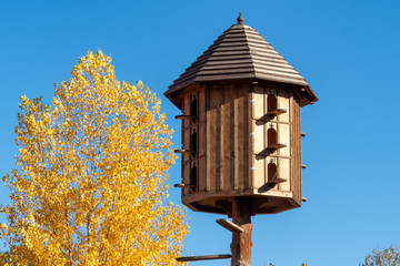 The wooden dovecote on the background of the blue sky. A large pigeon loft or dovecote. - Powered by Adobe