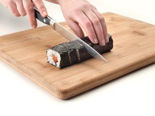 Rollo de sushi entero cortando con un cuchillo y posado sobre una tabla de cocina 2
