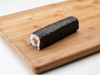 Rollo de sushi entero posado sobre una tabla de cocina