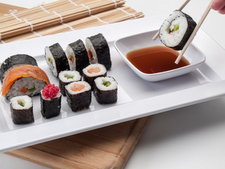 Bandeja con resultados de sushis y uno con palillos en primer plano