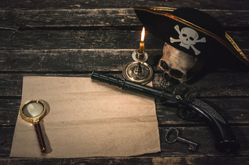 Pirate treasure map with copy space, pirate captain hat, human skull, musket, dagger and burning...