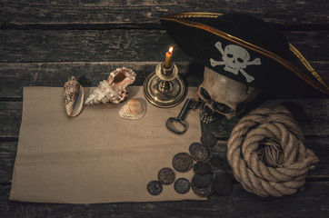 Pirate treasure map with copy space, pirate captain hat, coins, human skull, seashells, mooring rope and burning candle. Treasure hunter concept background.