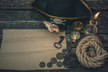 Pirate treasure map with copy space, pirate captain hat, compass, coins, seashell, mooring rope and burning candle. Treasure hunter concept background.