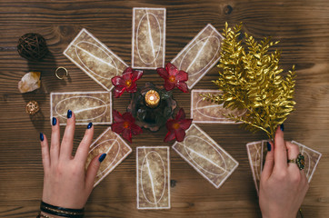 Tarot cards and hands of fortune teller on wooden table background.