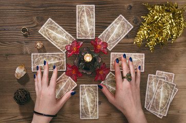 Tarot cards and hands of fortune teller on wooden table background.