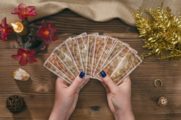 Tarot cards and hands of fortune teller on wooden table background.